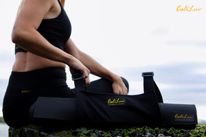 Person holding a black CaliLuv yoga mat carrier against a scenic background. Made in California and made with hemp.